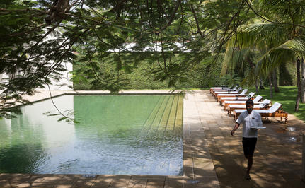 Wooden boardwalk beside a green plunge pool at Amangalla, with a figure standing on the deck surrounded by lush vegetation.