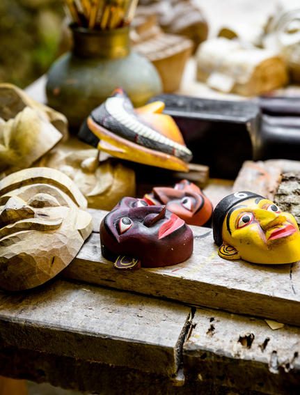 Wooden masks and carved figurines displayed on a weathered surface at Amangalla.