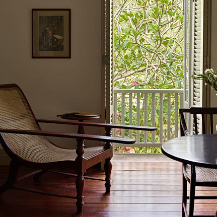 Wooden chairs beside a window with garden views at Amangalla, Sri Lanka.