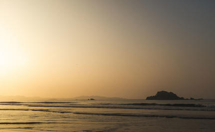 Sunrise over calm waters at Amangalla, with a distant island silhouetted against the golden sky.