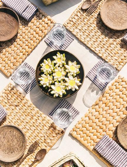 Overhead view of a plated salad at Amansara, surrounded by place settings and woven textiles.