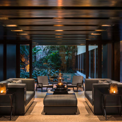 Amansara's open-sided pavilion with seating areas and garden views at dusk.