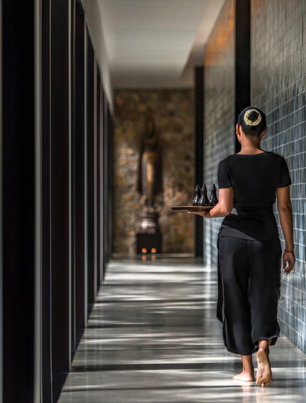 Woman in black dress walking through colonnade at Amansara.