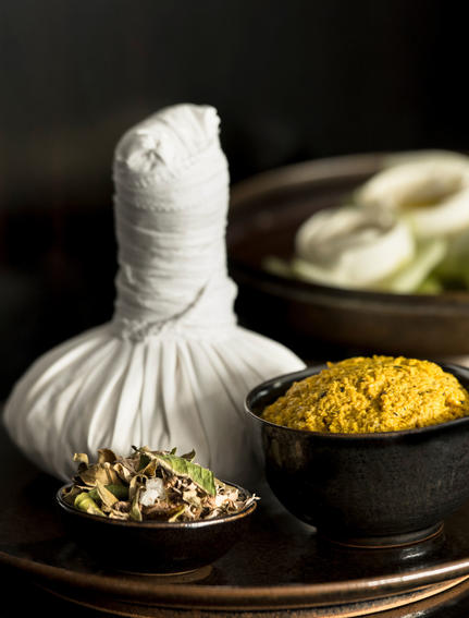 Herbal poultice and golden powder in bowls at Amansara's spa treatment area.