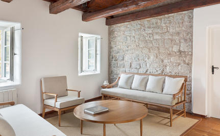 Deluxe cottage seating area at Aman Sveti Stefan with stone feature wall and wooden beams.