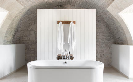 Freestanding stone bathtub with curved archway at Aman Sveti Stefan, Montenegro.