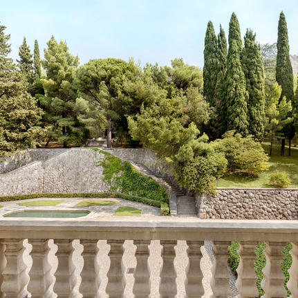 Stone balustrade overlooking manicured gardens with cypress trees at Aman Sveti Stefan, Montenegro.
