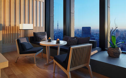 Premier Room seating area at Aman Tokyo with views across the city skyline at dusk.