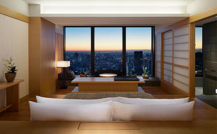 Principal bedroom at Aman Tokyo with floor-to-bed windows framing Tokyo's evening skyline.