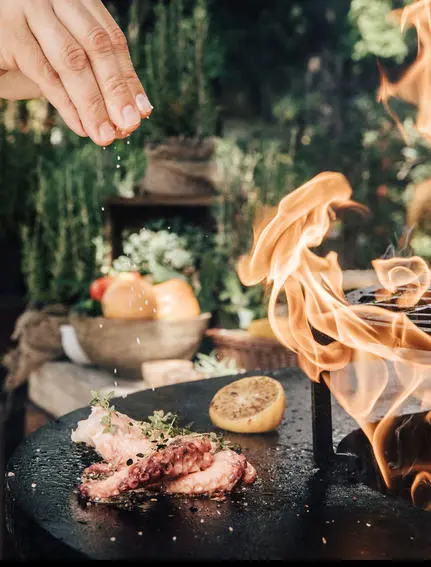 Hand pouring wine over grilled meat at Aman Sveti Stefan.