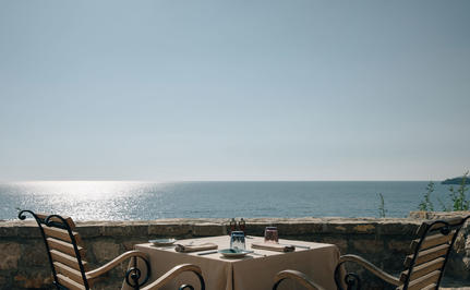 Dining piazza at Aman Sveti Stefan with views across the Adriatic Sea towards distant mountains.