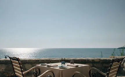 Dining piazza at Aman Sveti Stefan with views across the Adriatic Sea towards distant mountains.