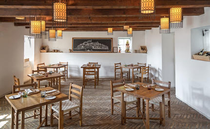 Dining piazza at Aman Sveti Stefan with wooden tables and chairs beneath pendant lighting.
