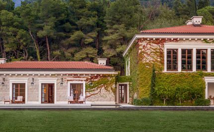 Wellness pavilion and main residence with terracotta roof at Aman Sveti Stefan, surrounded by green lawns and pine trees.