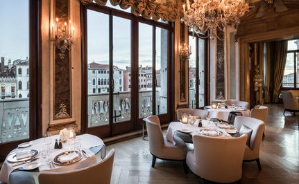 Sala da pranzo presso Aman Venice con tavoli eleganti e vista sul canale attraverso le finestre.