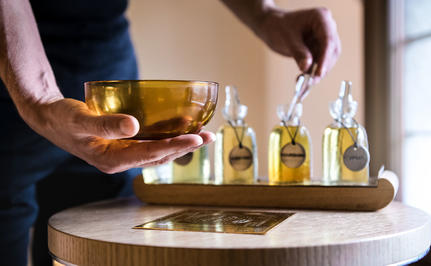 Hand pouring golden oil into a glass bowl at Aman Venice wellness experience.