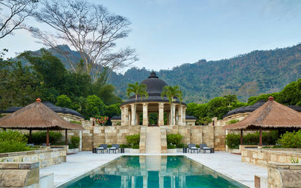 Amanjiwo's central courtyard with reflecting pool and traditional stone pavilion, surrounded by mountains and lush gardens.