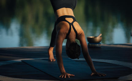 Yoga practitioner in downward dog pose at Amanyara's wellness facility, with water view behind.