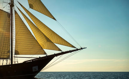 Sailing vessel with yellow canvas at Amandira, Indonesia, captured against a clear sky and sea.