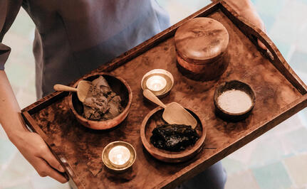 Wellness ritual display at Amanjena with natural skincare products arranged on a wooden tray.