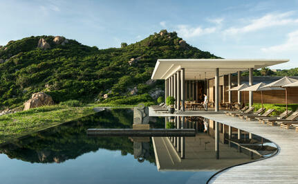 安缦诺怡度假村的餐饮场所，木质建筑映照在平静池水中，周围绿树环抱。