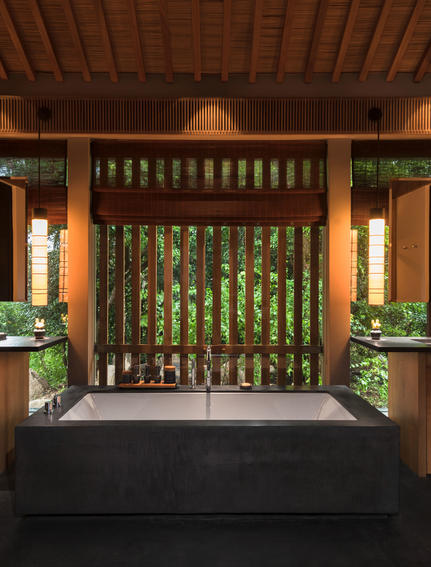 Amanoi entrance hall with wooden slat doors, warm lighting, and potted plants flanking the doorway.