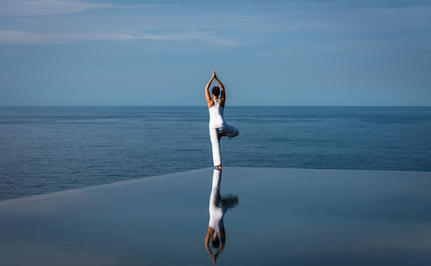 Woman in white dress standing on still water at Amanoi, reflected in the surface below.