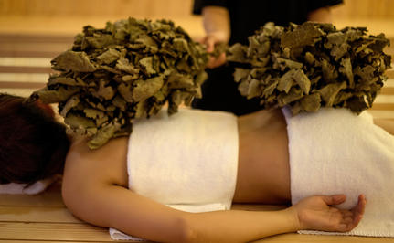 Amanoi gallery: Spa treatment detail showing hands holding fresh herbs and white towel.