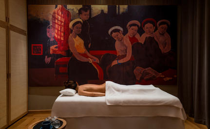 Spa treatment room at Amanoi with massage table, folded towels, and artwork on wall.