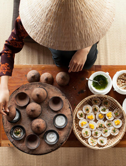 Overhead view of a traditional Vietnamese conical hat beside a wooden tray of quail eggs and bowls of ingredients at Amanoi.