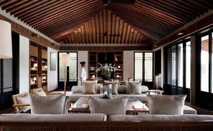 Amanoi dining venue with wooden vaulted ceiling, floor-to-ceiling windows, and round tables set for service.
