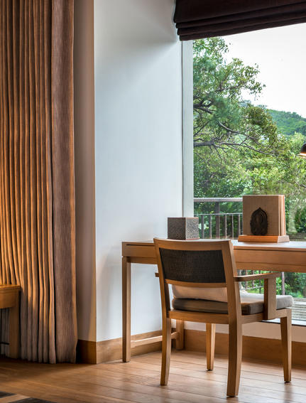 Wooden desk and chair beside large window with mountain views at Amanoi.