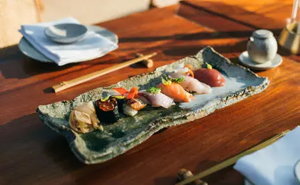 Nama dining experience at Amanpuri resort, featuring fresh seafood selections on a ceramic platter with garnishes and condiments.