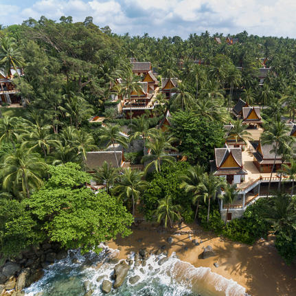 Amanpuri's pavilions nestled amongst dense tropical forest canopy overlooking a flowing river below.