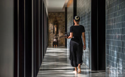 Woman walking through a modern corridor at Amansara wellness retreat.
