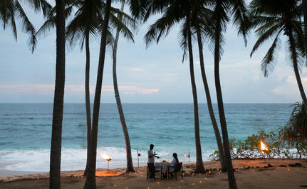 Dining pavilion framed by palm trees overlooking the Indian Ocean at Amanwella.