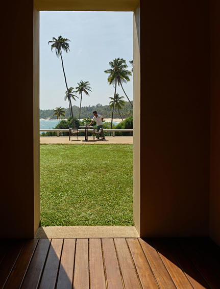 View from a pavilion across manicured lawns and palm trees towards the Indian Ocean at Amanwella.