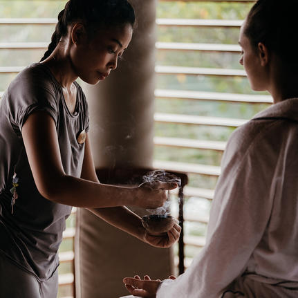 Two staff members exchanging a woven basket at Amanyara resort.