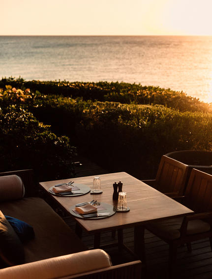 Dining table at sunset overlooking forested landscape at Amanyara resort.