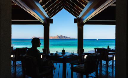 Dining room at Amanpulo with turquoise waters and island views framed by open windows.