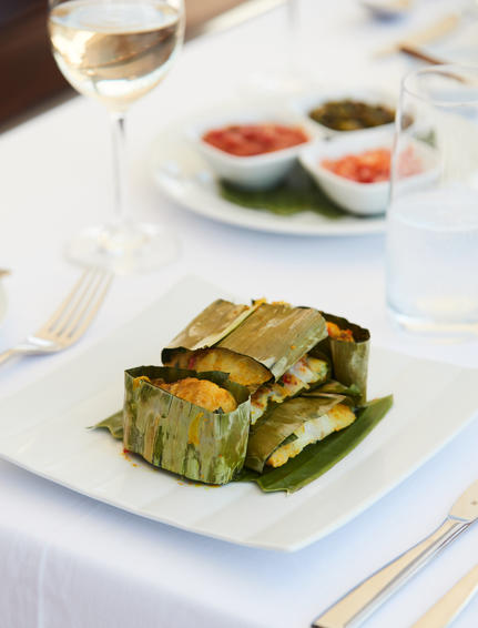 Grilled courgette slices arranged on a white plate at Amandira, with a fresh salad and white wine in the background.