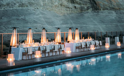 Candlelit wedding setup reflected in still water at Amangiri, with red rock cliff backdrop.