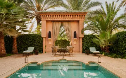 Plunge pool in a walled garden courtyard at Amanjena resort, surrounded by terracotta walls and palm trees.