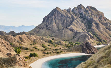 Dramatic volcanic peak rising above a crescent beach at Amandira, Indonesia.