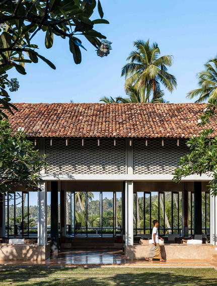 Pavilion with terracotta roof at Amanwella, framed by palm trees and tropical foliage.