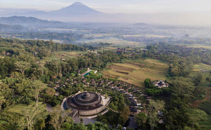Vue aérienne d'Amankila, resort en Indonésie, avec rizières et volcan en arrière-plan.