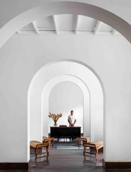 Ben Richards photograph of a vaulted corridor at Amangalla with a piano and wooden chairs visible through the archway.