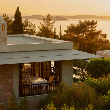 Amanruya dining venue at sunset overlooking the Turkish coastline and sea.