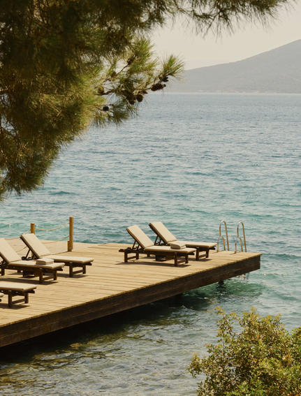 Wooden jetty with loungers extending into turquoise waters at Amanruya, Turkey.