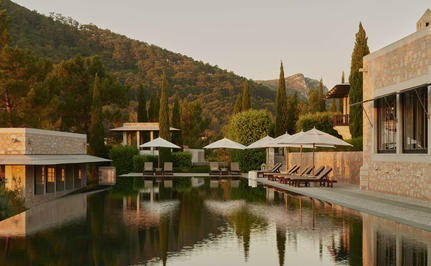 Main pool at Amanruya, Turkey, reflecting surrounding mountains and cypress trees.